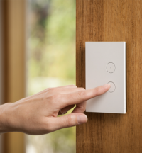 A finger pushing the LED push button switch on a Clipsal Saturn Zen switch